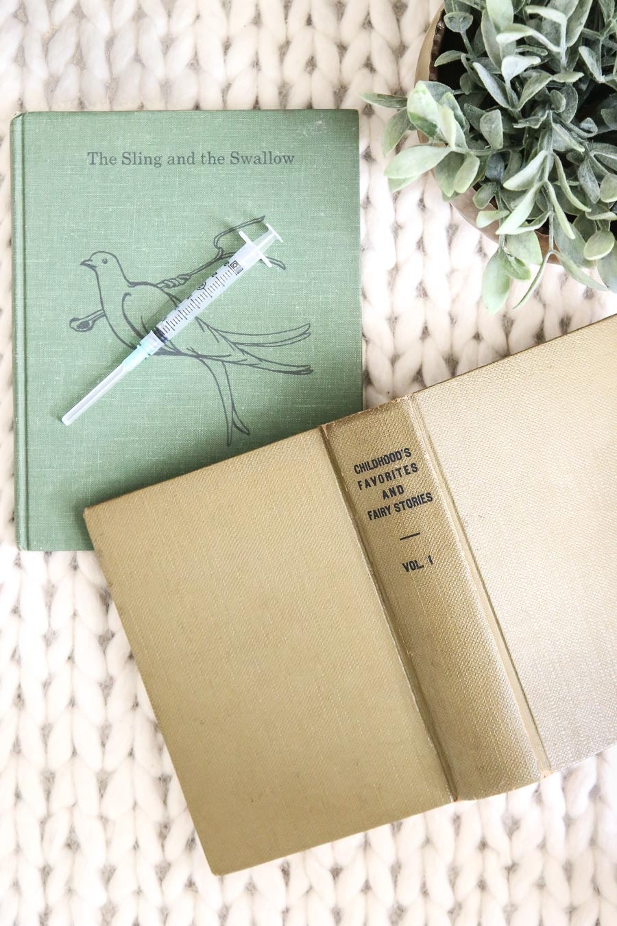 Two children's books with an IVF needle on a beautiful wool rug, signifying infertility